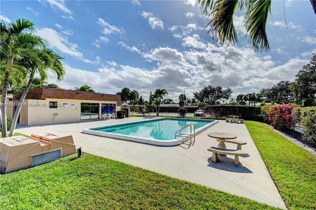 view of swimming pool featuring a patio and a yard