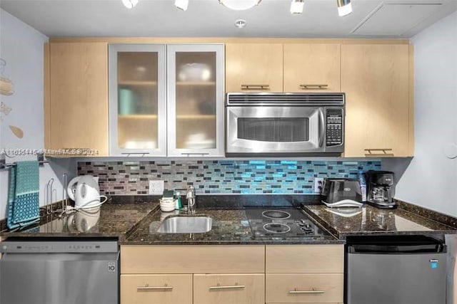 kitchen featuring dark stone counters, decorative backsplash, light brown cabinetry, and stainless steel appliances