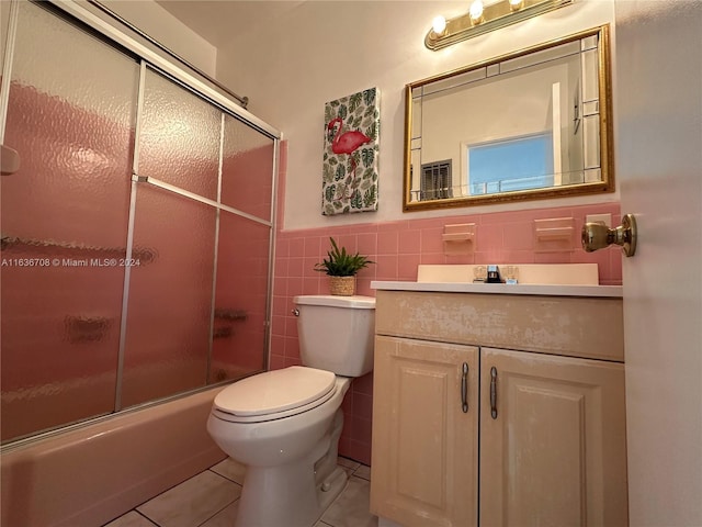 full bathroom featuring tile patterned floors, vanity, tile walls, enclosed tub / shower combo, and toilet