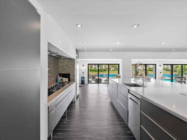 kitchen featuring premium range hood, sink, appliances with stainless steel finishes, backsplash, and dark wood-type flooring