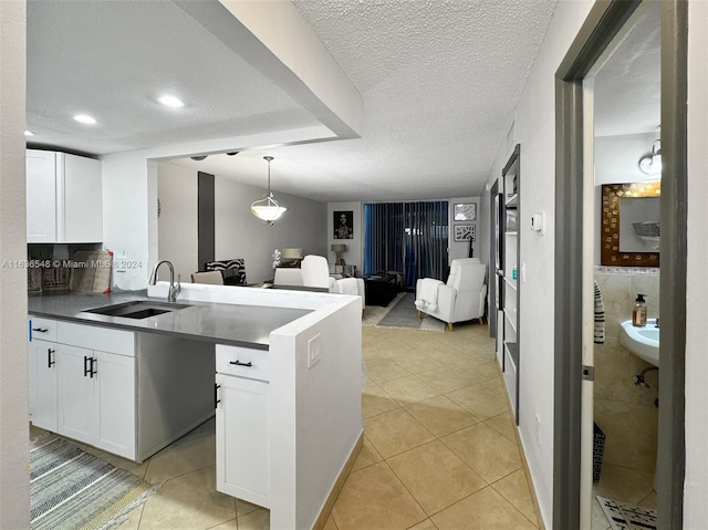 kitchen with white cabinets, light tile patterned floors, decorative light fixtures, and sink