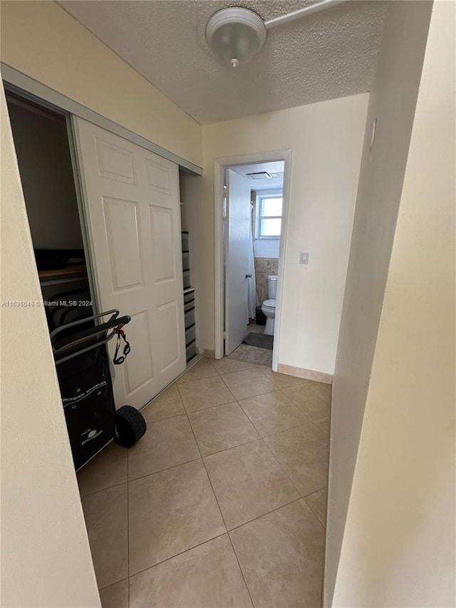 corridor featuring light tile patterned floors and a textured ceiling