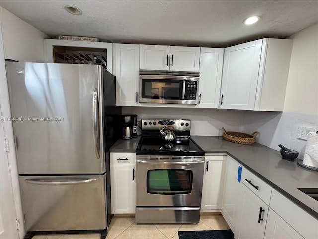 kitchen with white cabinets, stainless steel appliances, and light tile patterned floors