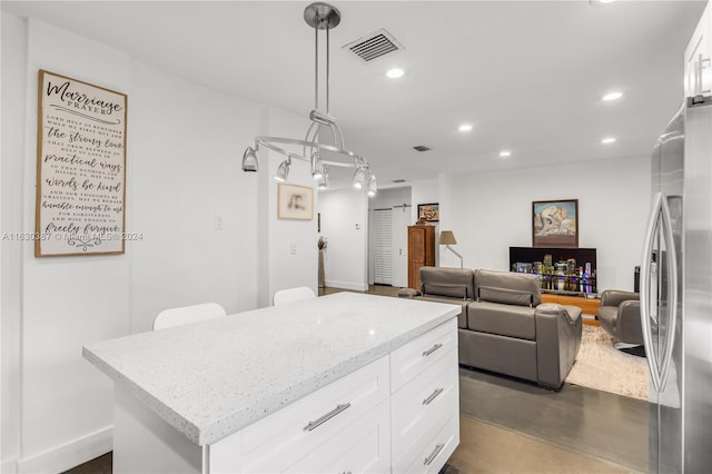 kitchen with white cabinetry, a center island, light stone counters, dark hardwood / wood-style floors, and decorative light fixtures