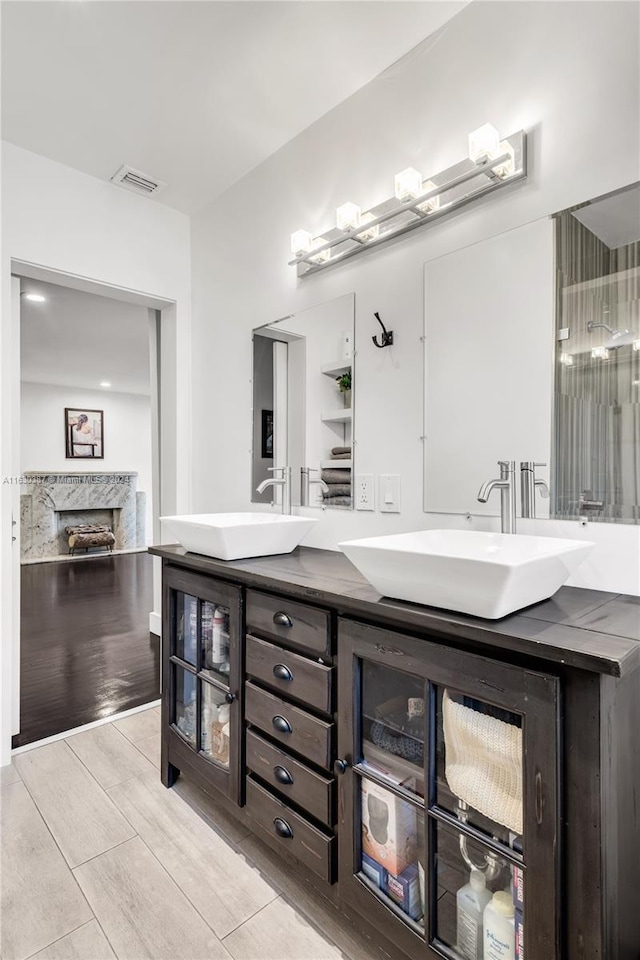 bathroom featuring a fireplace, wood-type flooring, and double sink vanity