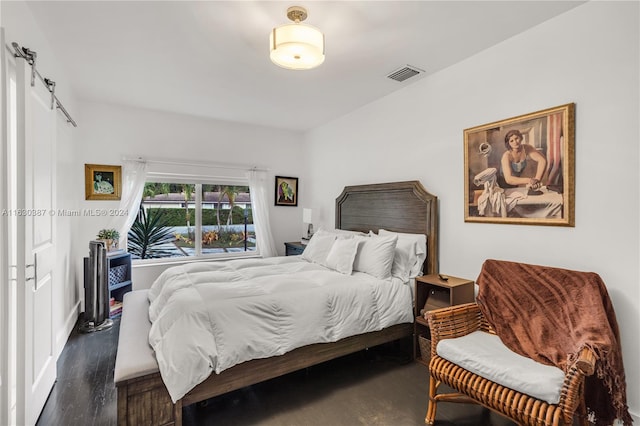 bedroom with dark hardwood / wood-style floors and a barn door