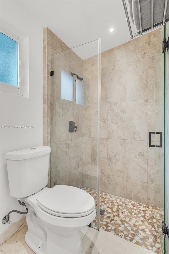 bathroom with an enclosed shower, toilet, and tile patterned floors