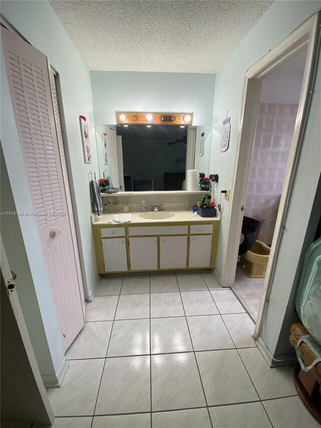 bathroom with vanity, a textured ceiling, toilet, and tile patterned flooring