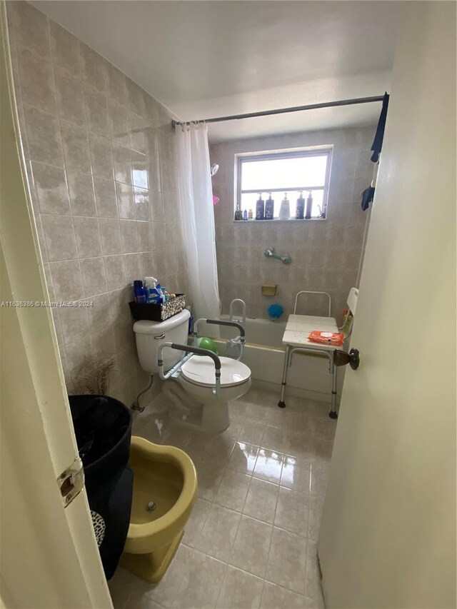 bathroom with toilet, tile walls, tile patterned floors, a bidet, and shower / bathtub combination with curtain