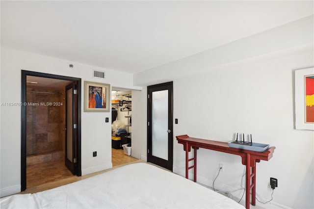 bedroom featuring light hardwood / wood-style floors, a closet, connected bathroom, and a walk in closet