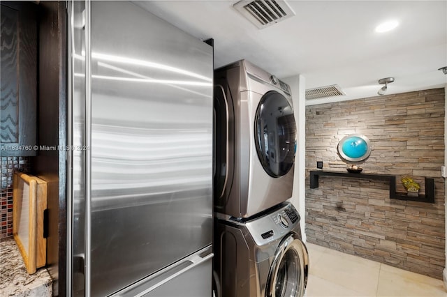 washroom with light tile patterned flooring and stacked washer and dryer