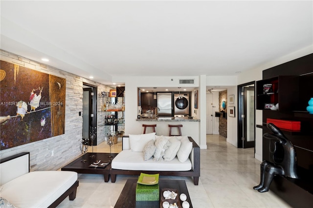 living room with light tile patterned flooring and stacked washer / dryer