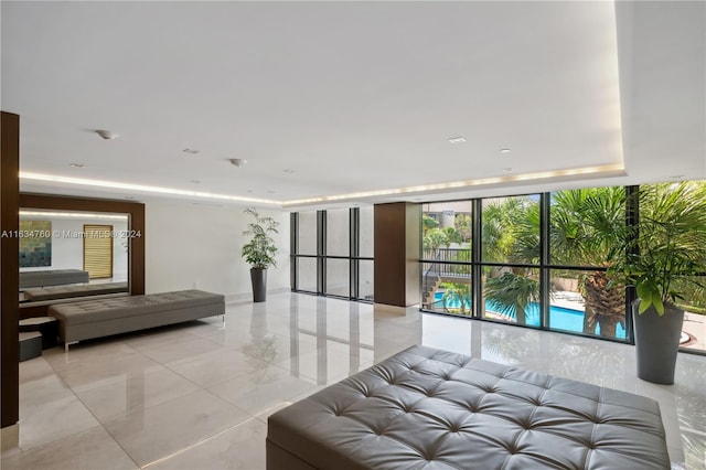 tiled bedroom featuring access to exterior, expansive windows, and a tray ceiling