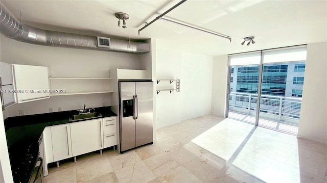 kitchen with expansive windows, sink, and stainless steel refrigerator with ice dispenser