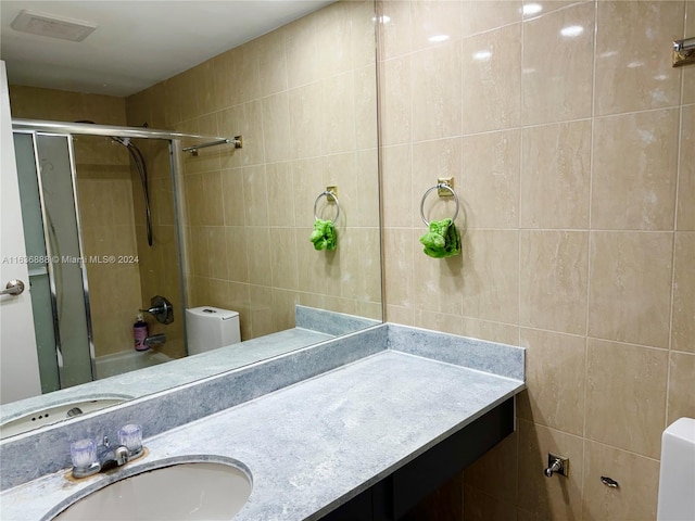 bathroom with vanity, tile walls, and toilet