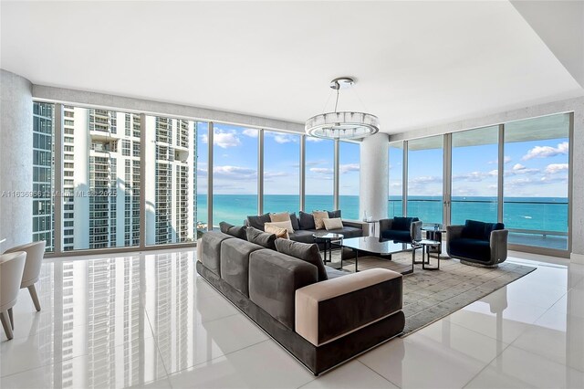 living room featuring a water view, light wood-type flooring, a fireplace, and an inviting chandelier