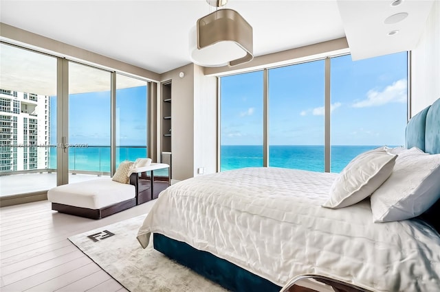 bedroom featuring access to exterior, a water view, and wood finished floors