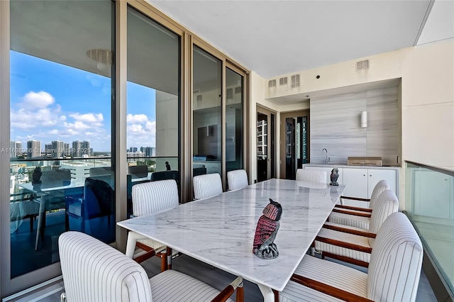 dining room with expansive windows, a view of city, and visible vents