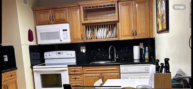 kitchen featuring sink, white appliances, dark stone counters, and backsplash