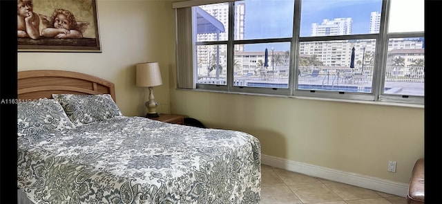 bedroom with a city view, multiple windows, baseboards, and tile patterned flooring