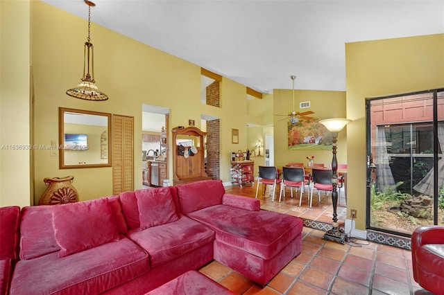 tiled living room with ceiling fan and high vaulted ceiling