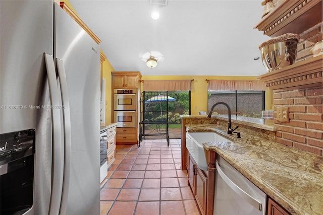 kitchen with tile patterned floors, light stone counters, sink, and appliances with stainless steel finishes