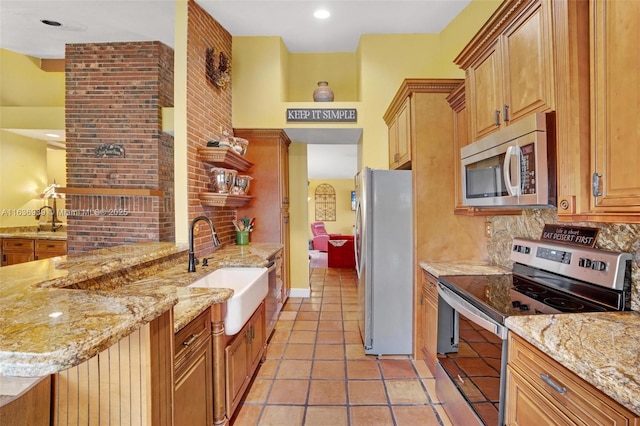 kitchen with light stone countertops, stainless steel appliances, light tile patterned flooring, and sink