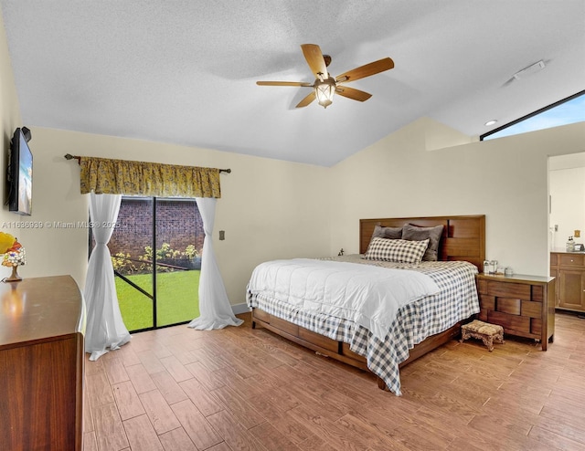 bedroom featuring ceiling fan, ensuite bathroom, a textured ceiling, vaulted ceiling, and access to outside