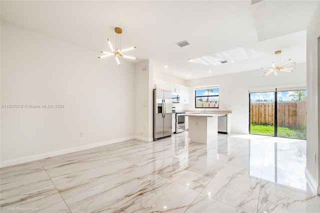 interior space featuring appliances with stainless steel finishes, white cabinets, light tile patterned floors, and a chandelier