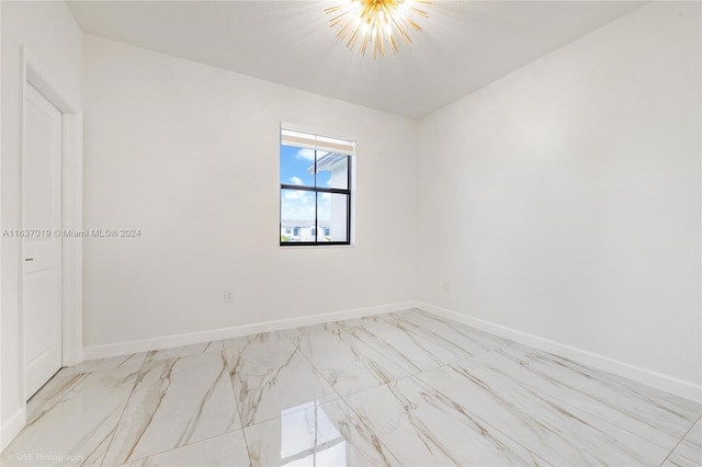 empty room with a chandelier and light tile patterned floors