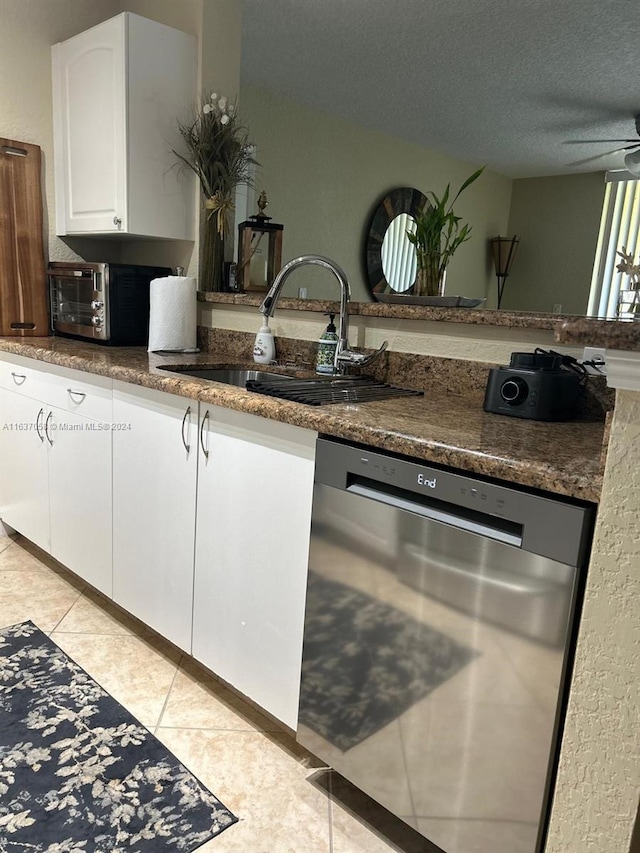 kitchen with light tile patterned floors, white cabinets, ceiling fan, stainless steel dishwasher, and sink