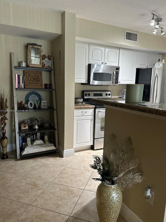 kitchen with appliances with stainless steel finishes, a textured ceiling, rail lighting, and white cabinetry