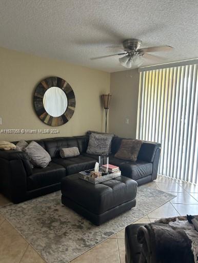 living room with a textured ceiling, light tile patterned floors, and ceiling fan