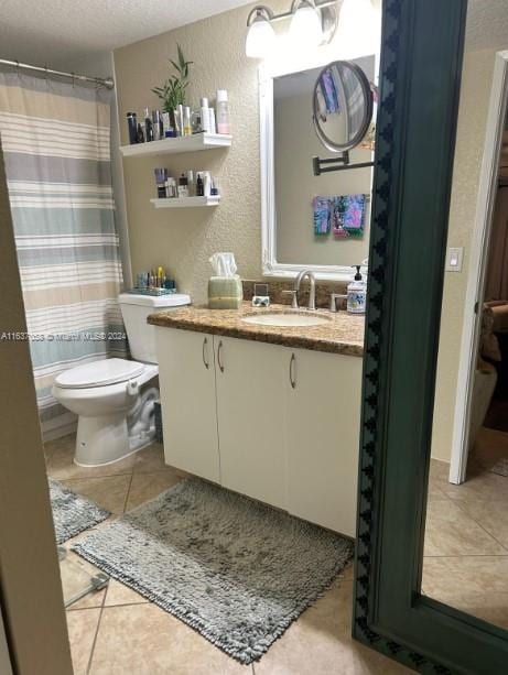 bathroom with tile patterned flooring, toilet, vanity, and a textured ceiling