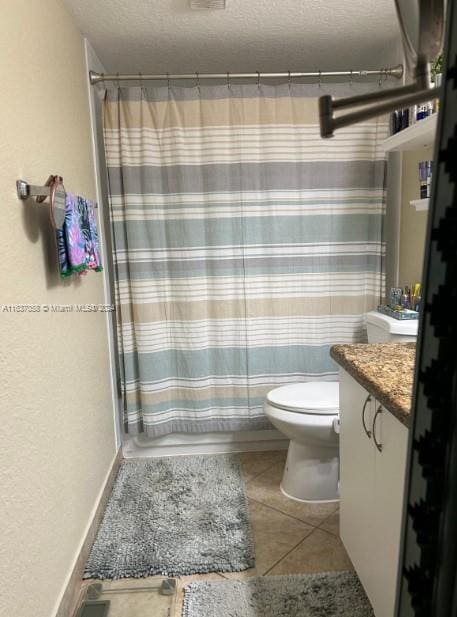 bathroom with vanity, toilet, tile patterned floors, and a textured ceiling