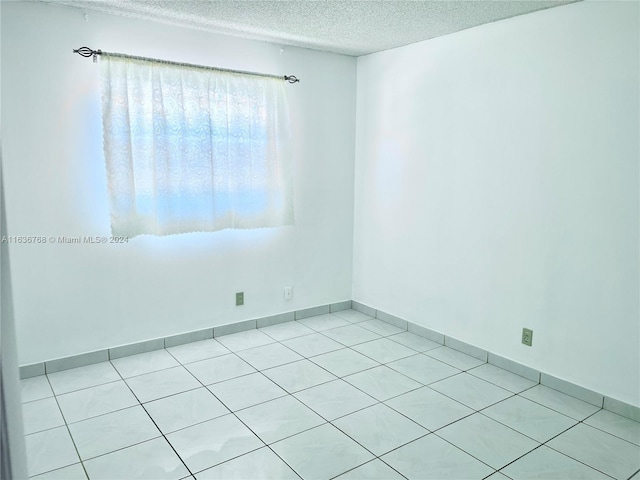 unfurnished room with a textured ceiling and light tile patterned floors