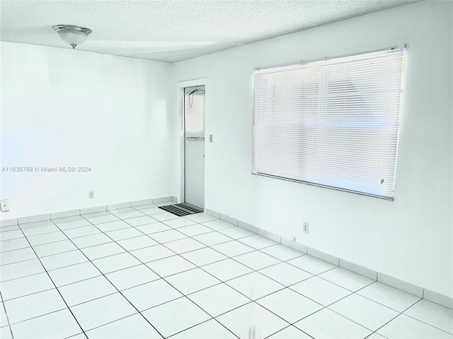 spare room with light tile patterned floors and a textured ceiling