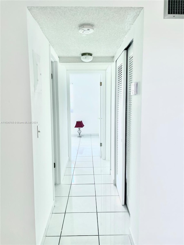 hall featuring light tile patterned floors and a textured ceiling