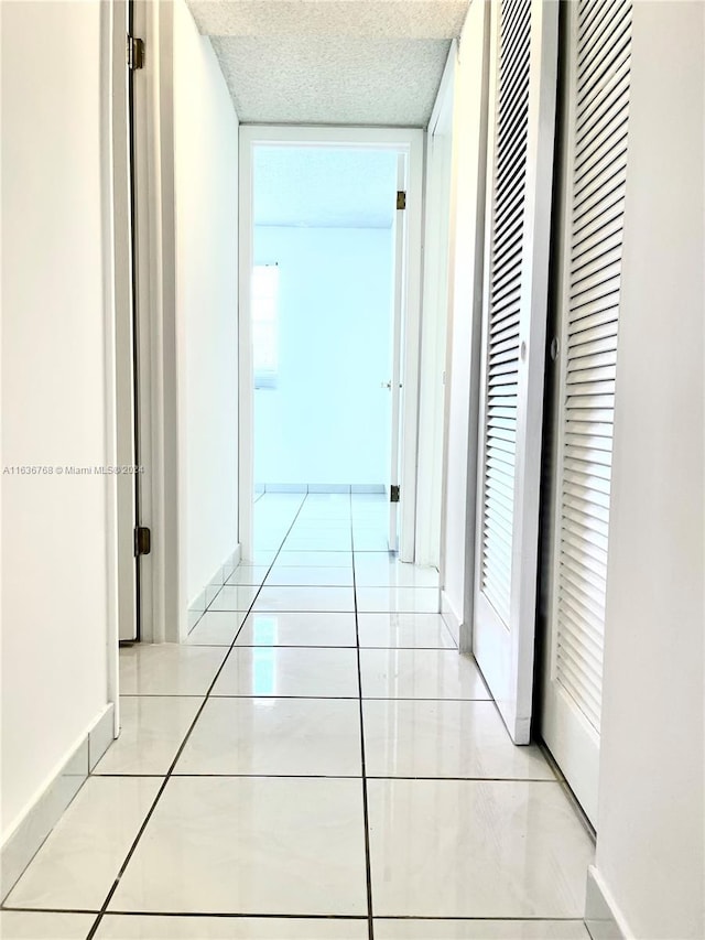 hallway with a textured ceiling and light tile patterned floors