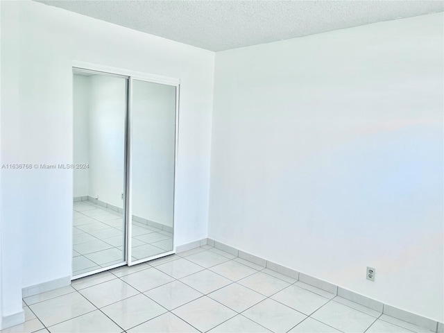 unfurnished bedroom featuring a closet, light tile patterned floors, and a textured ceiling