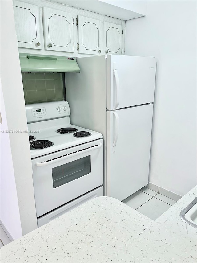 kitchen featuring light tile patterned flooring, extractor fan, and white appliances