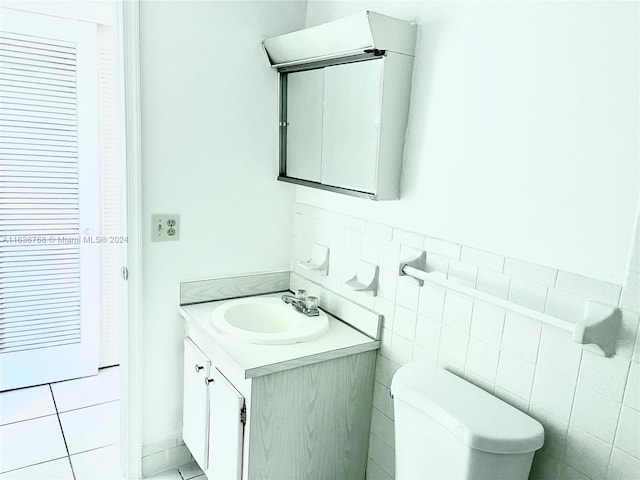 bathroom with tile walls, tile patterned floors, toilet, and vanity