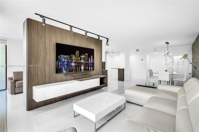 tiled living room featuring track lighting and an inviting chandelier