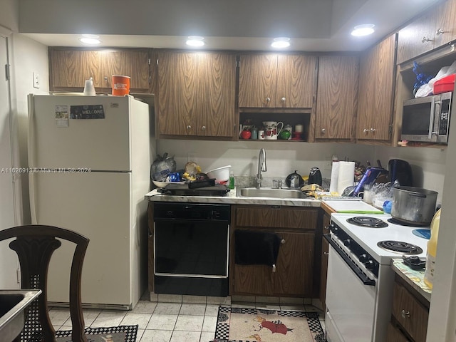 kitchen with white appliances, light tile patterned floors, dark brown cabinetry, and sink