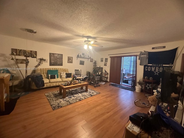 living room featuring ceiling fan, hardwood / wood-style flooring, and a textured ceiling