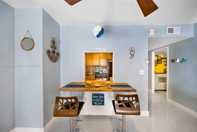 interior space featuring light tile patterned floors, baseboards, and visible vents