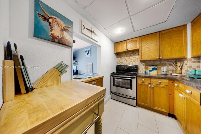 kitchen featuring stainless steel range with electric stovetop, light tile patterned floors, and backsplash