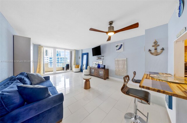 tiled living room with floor to ceiling windows and ceiling fan