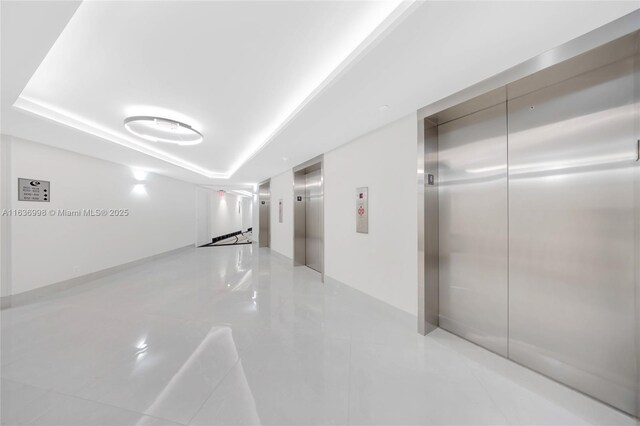 hall featuring light tile patterned flooring and elevator