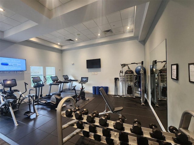 workout area with a drop ceiling, a towering ceiling, and a tray ceiling